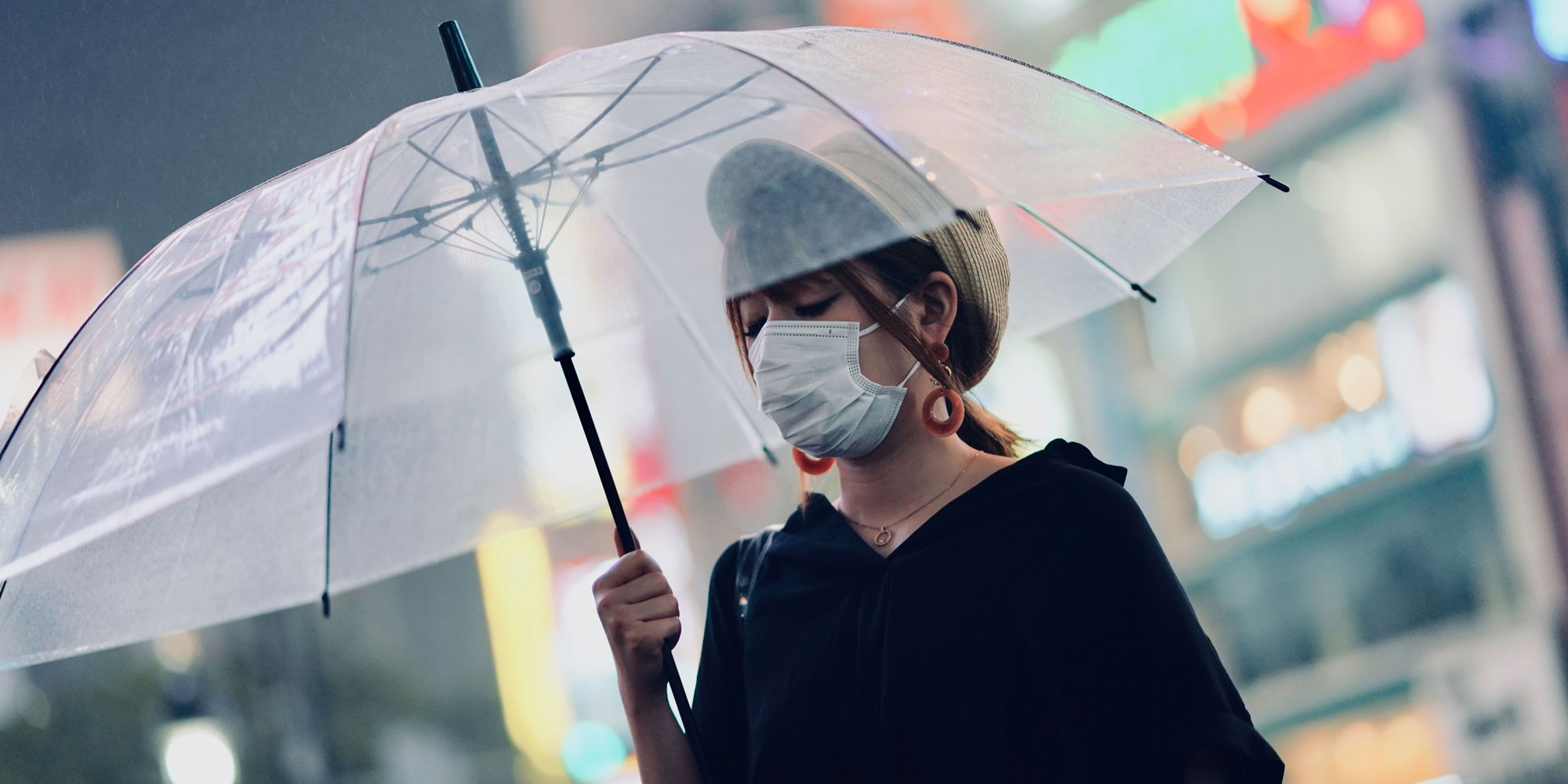woman wearing surgical mask, holding an umbrella