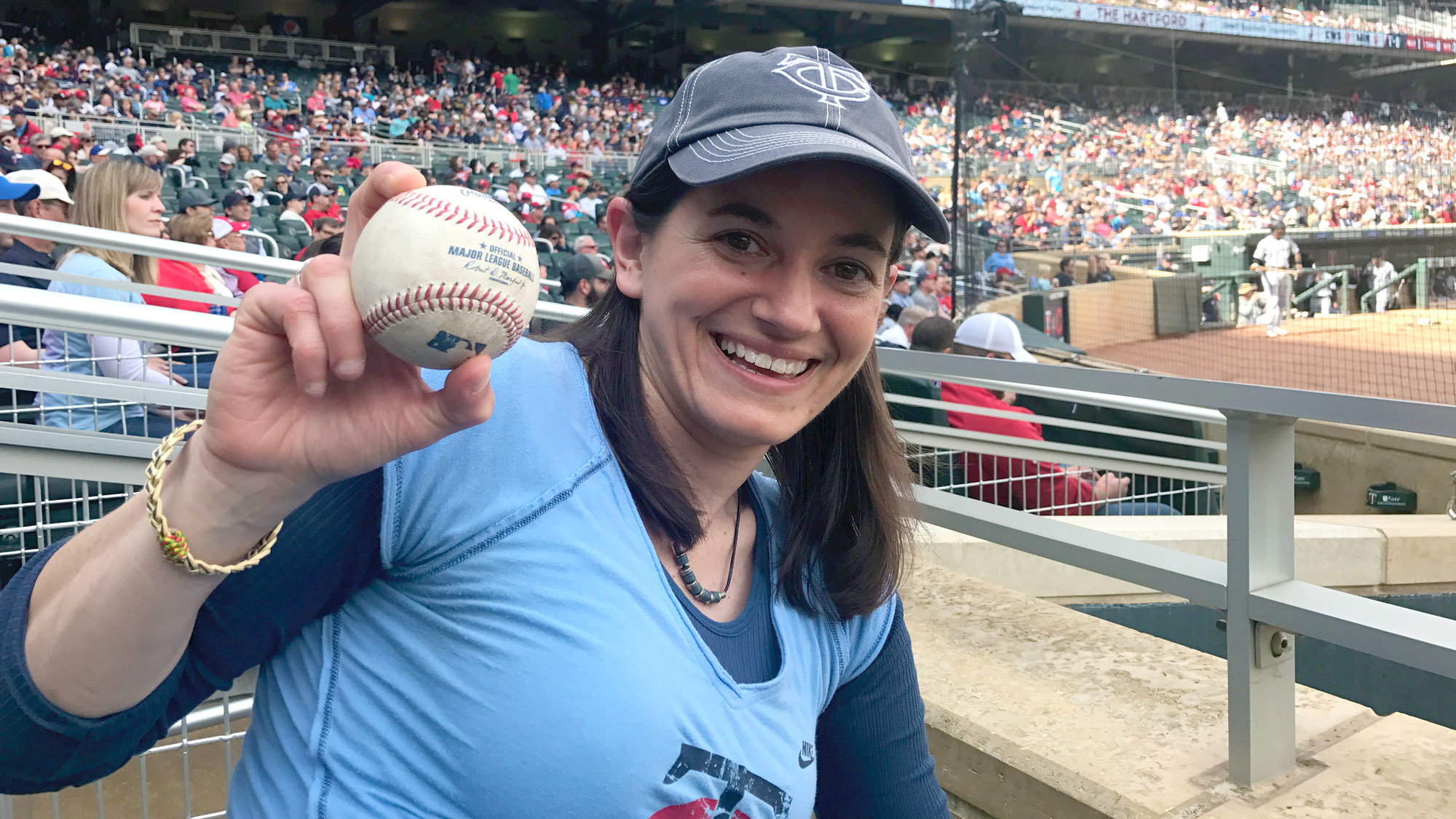 Larissa Minicucci holds up a baseball at a Twins game