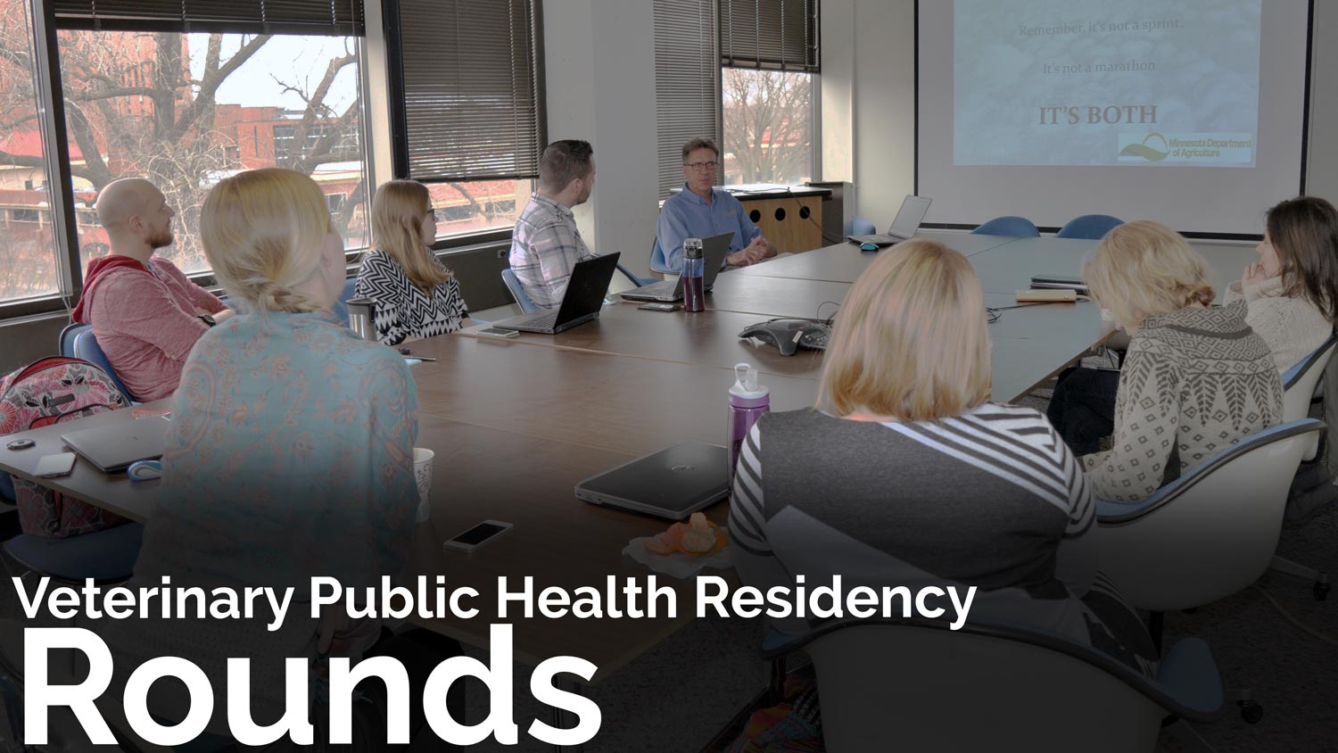 residents listening to a rounds presentation; text on image says "Veterinary Public Health Residency Rounds"